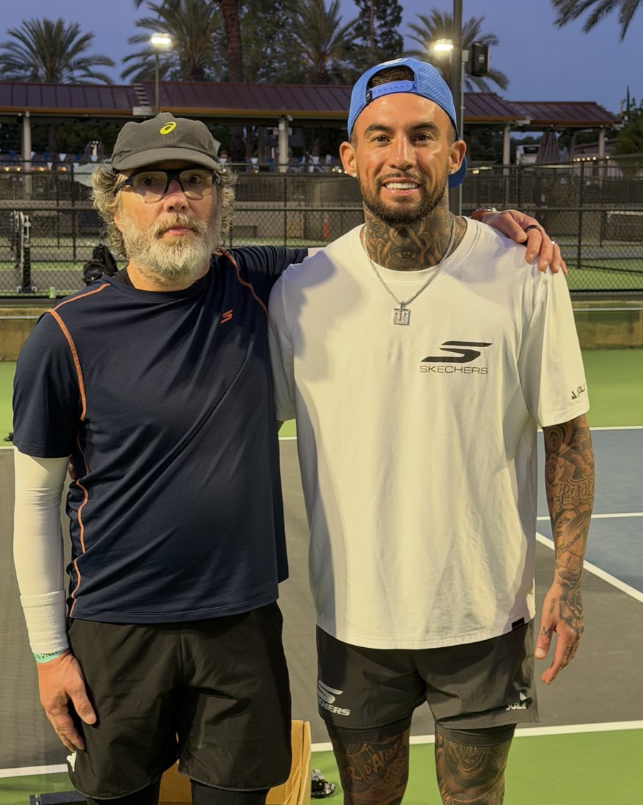 The scout standing arm in arm with a pro on a court at dusk